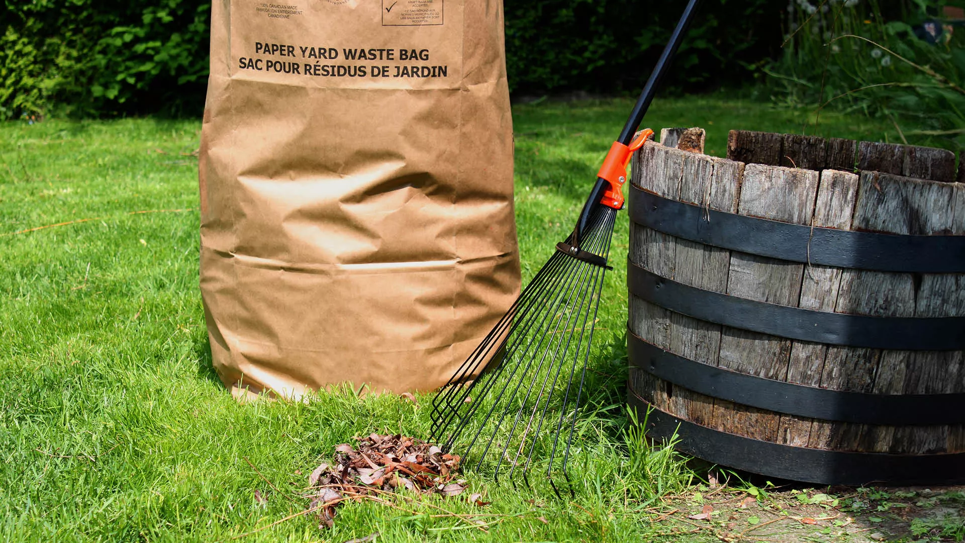 a kraft paper bag, rake and bucket on grass