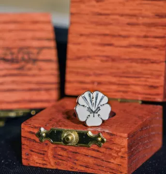 White flower pin with the City of Vaughan's logo engraved. Pin is in a wooden box.
