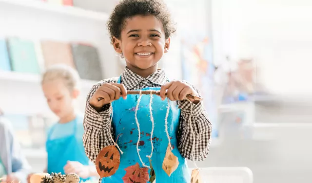 Child holding fall themed craft