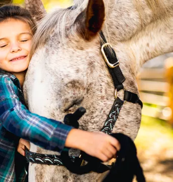 Young girl hugging a horse
