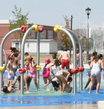 Splash pad in the park with kids playing in it.