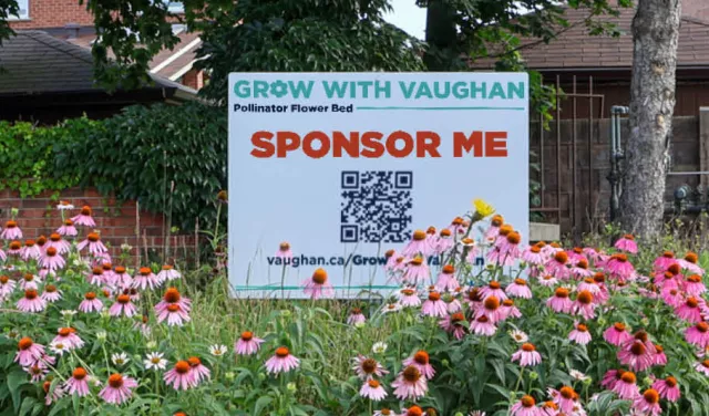 A sign in front of a bed of flowers