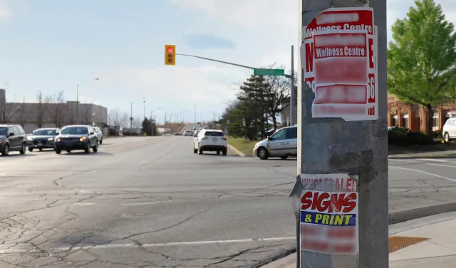Utility pole at a busy Vaughan intersection covered with illegal business signs