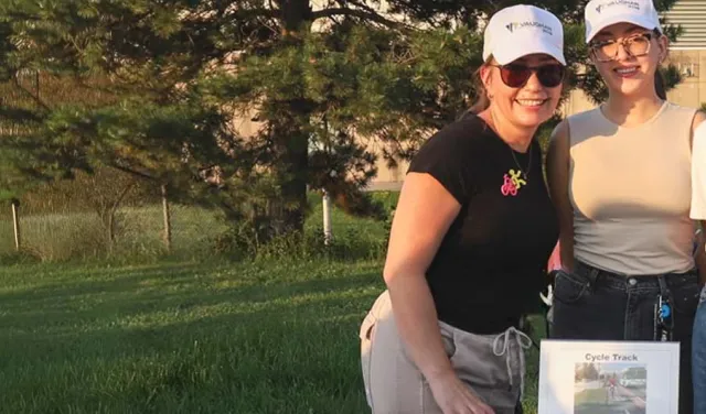 Three people outdoors behind an information table