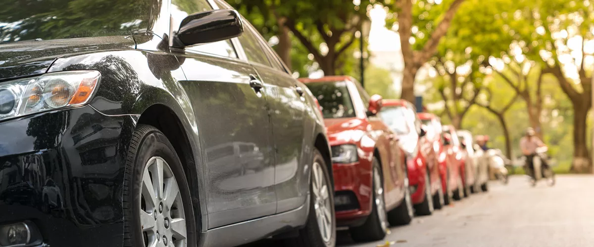 A group of cars parked in a line along a street.