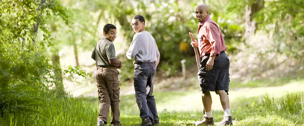 Three people walking through a trail.