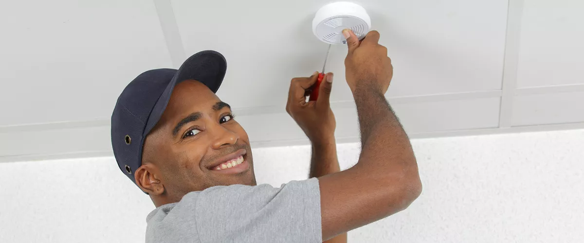 A person servicing a smoke detector.