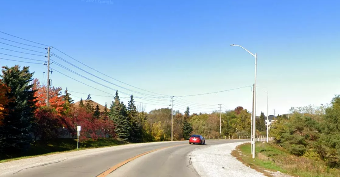 Image is of McNaughton Road in Maple with a car driving on it in the distance.