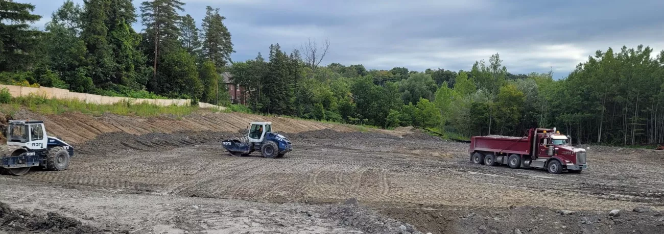 Image is of three trucks moving excess soil in an open area.