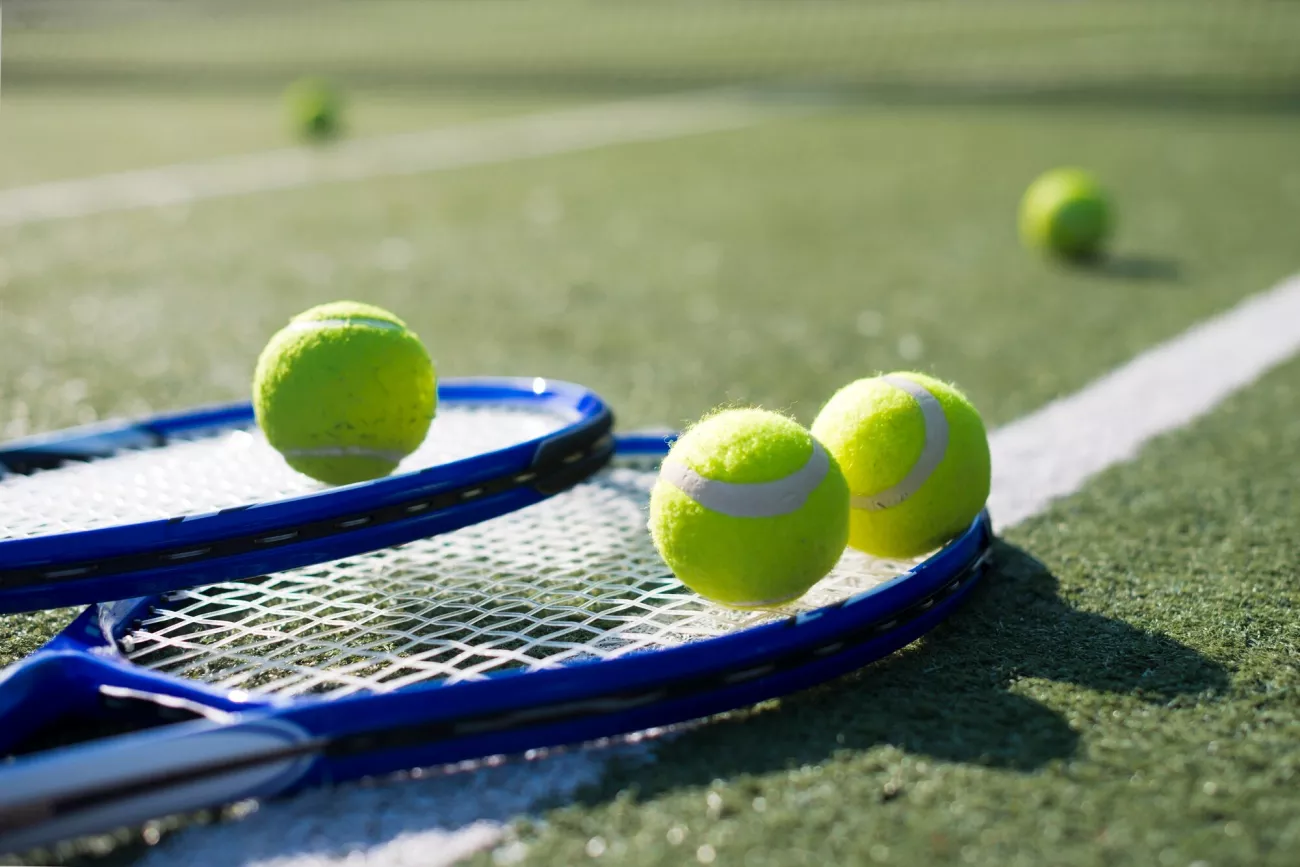 Image is of a tennis racquet and tennis balls 