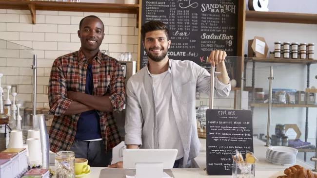 two men standing behind a cafe counter