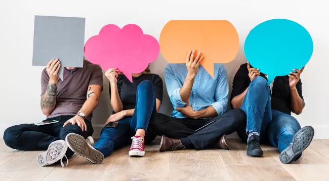 Four people holding chat bubbles over their faces.