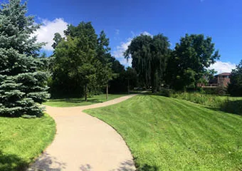 Multi-use trail adjacent to homes, bordered by grass and trees.
