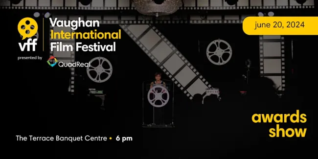 A women presenting an award on stage decorated with giant movie films.