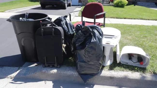 garbage bags, a red chair, suitcase and toilet at the curb