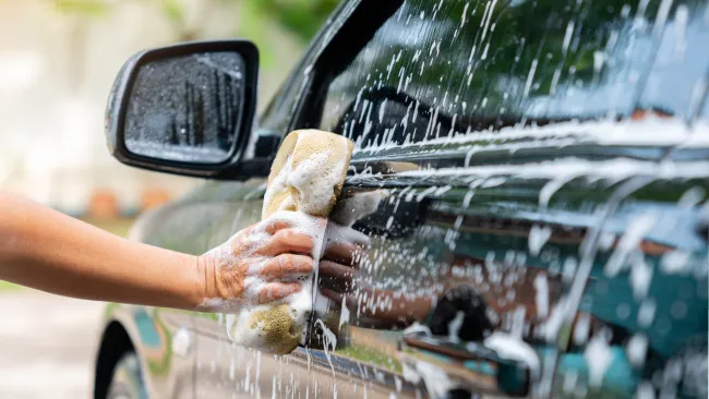 someone washing a black car with a sponge