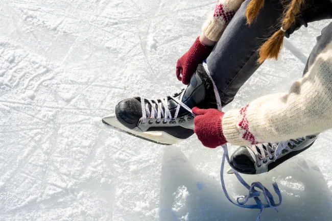 A female leaning over to tie her ice skates