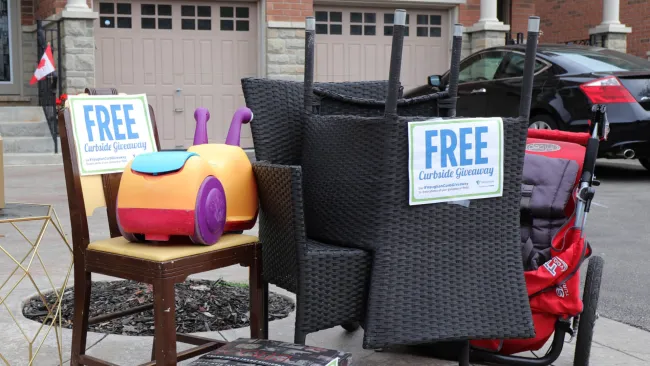 Chairs and toys curbside with "FREE" sign on them