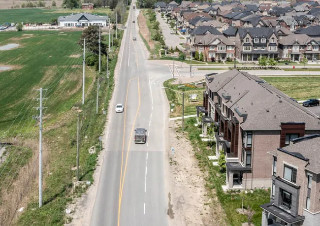 An aerial image of Huntington road showing cars driving along the road and homes on the right hand side.