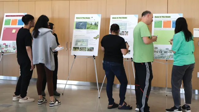A group of people looking at boards on easels at a community centre.