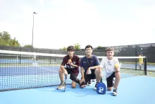 A Vaughan pickleball instructor and two boys posing on the outdoor pickleball court at Carrville Community Centre