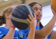 Two people holding basketballs preparing for a shot.