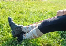 A pair of legs, ankle high argyle socks and black ankle-high paddock riding boots