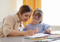 women helping young girl with special needs with school work