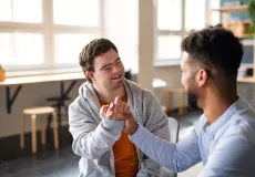 teenage boy with special needs shaking the hand of another individual