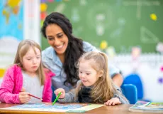 support person assisting 2 young girls with disabilites