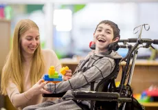 boy in a wheelchair playing blocks with women