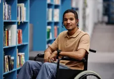 young adult with a disability smiling in a library