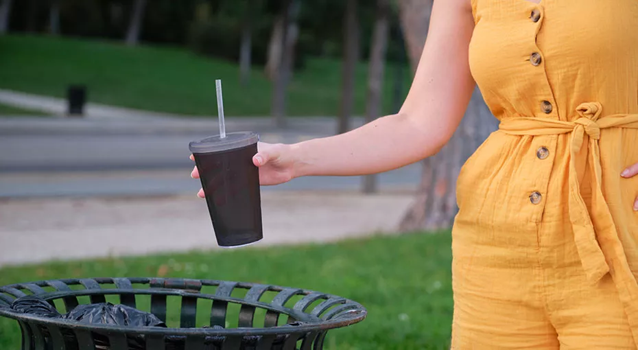 someone throwing a cup into the garbage
