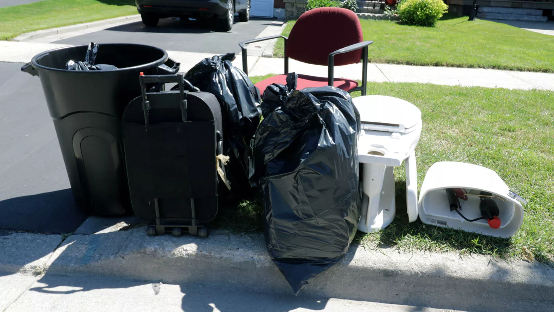 garbage bags, toilet, chair at the curb