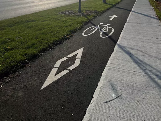 Image shows an in-boulevard multi-use pathway, which is marked by a diamond symbol and bicycle symbol.