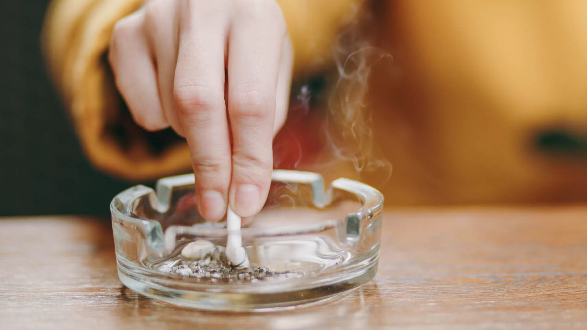 Someone extinguishing a cigarette in an ash tray