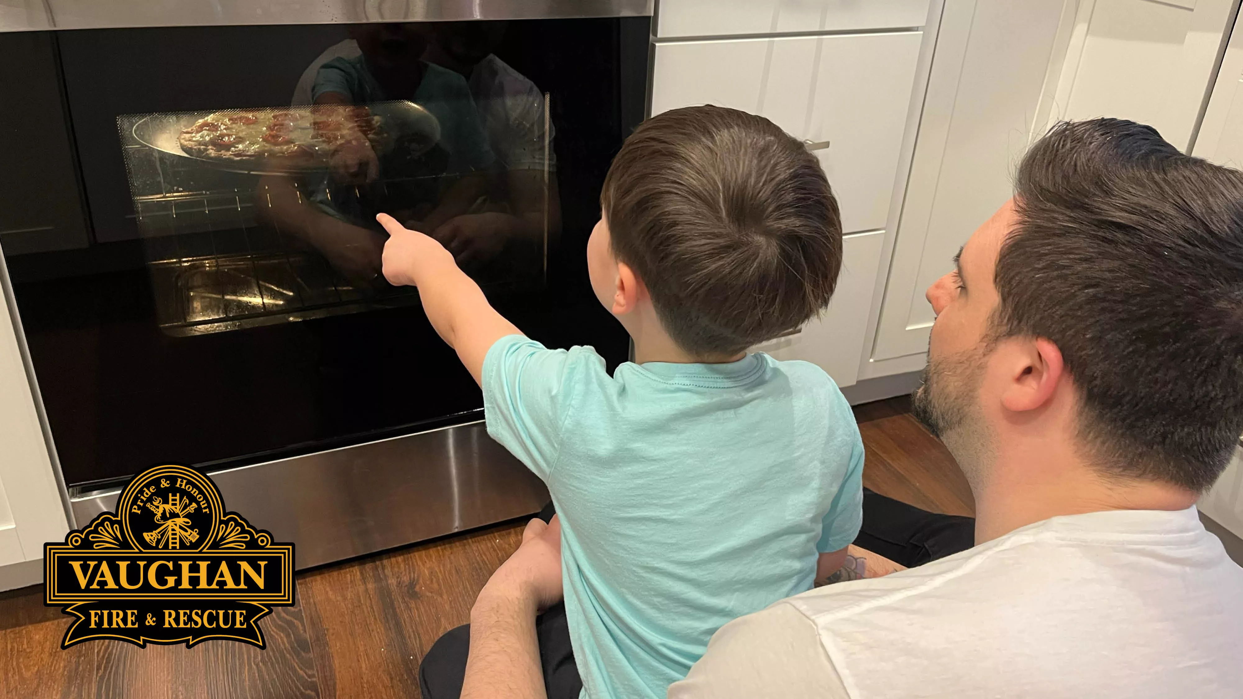 A man and a young boy watching a pizza cook in the oven. 