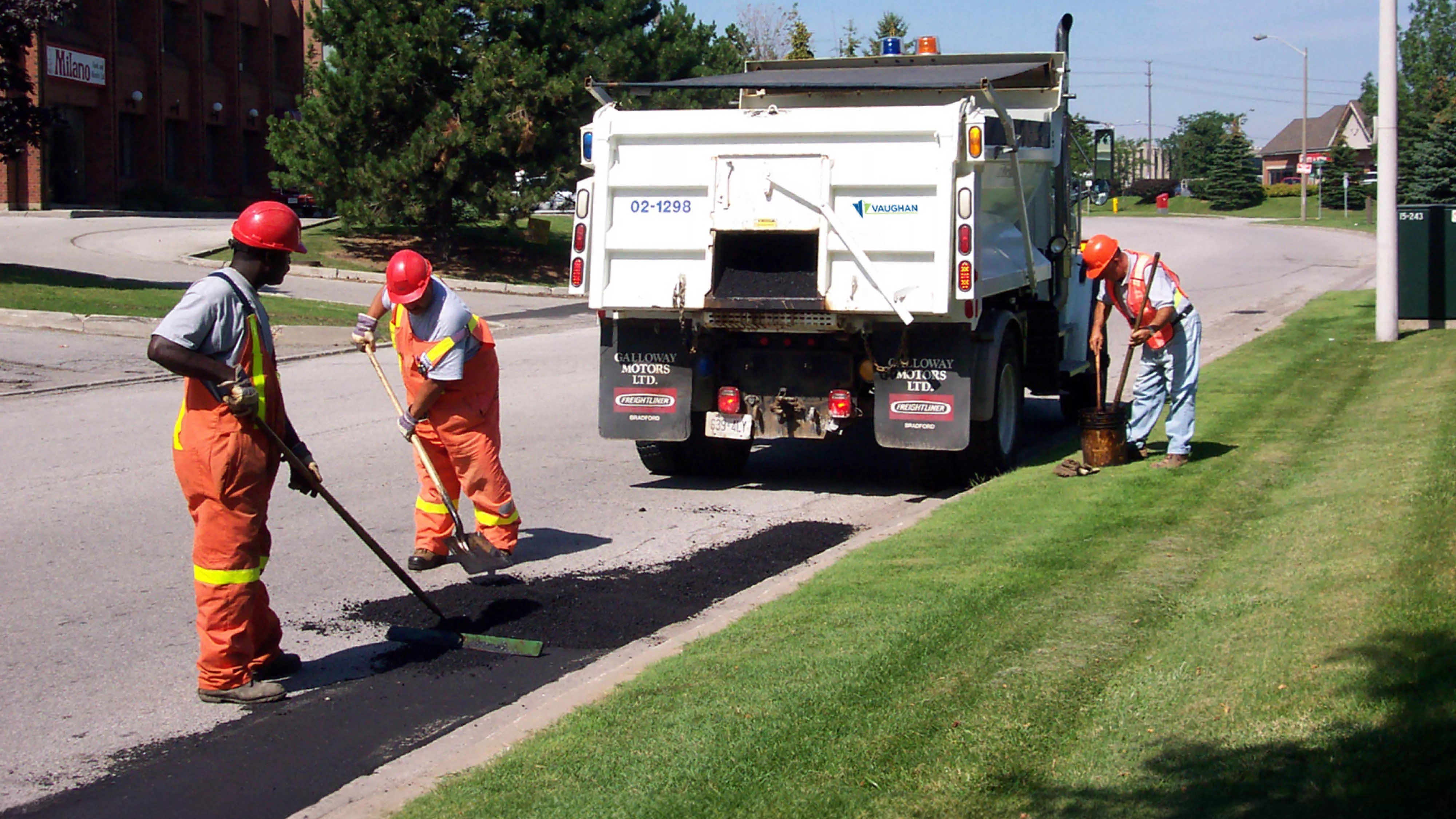 Three man crew working on a street patching holes