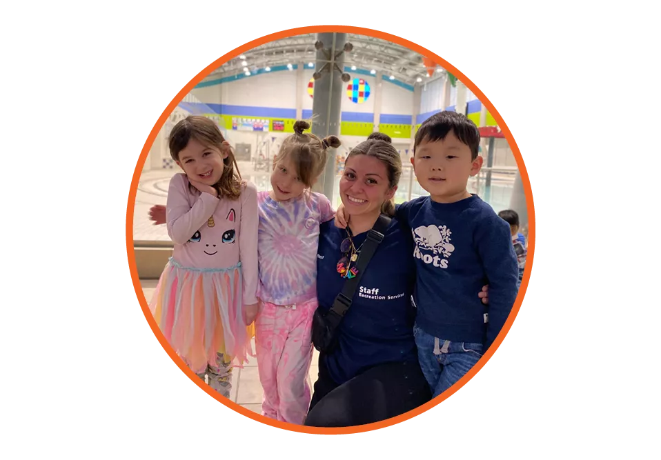 A camp counsellor posting with three young campers.