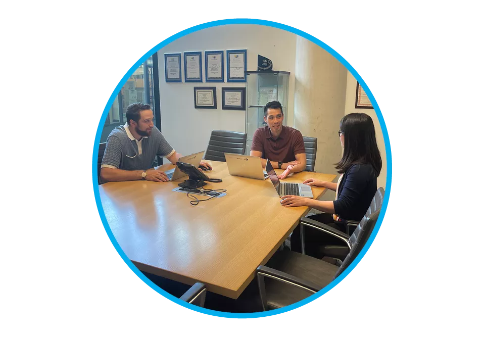 A group of three employees sitting at a boardroom table having a conversation.