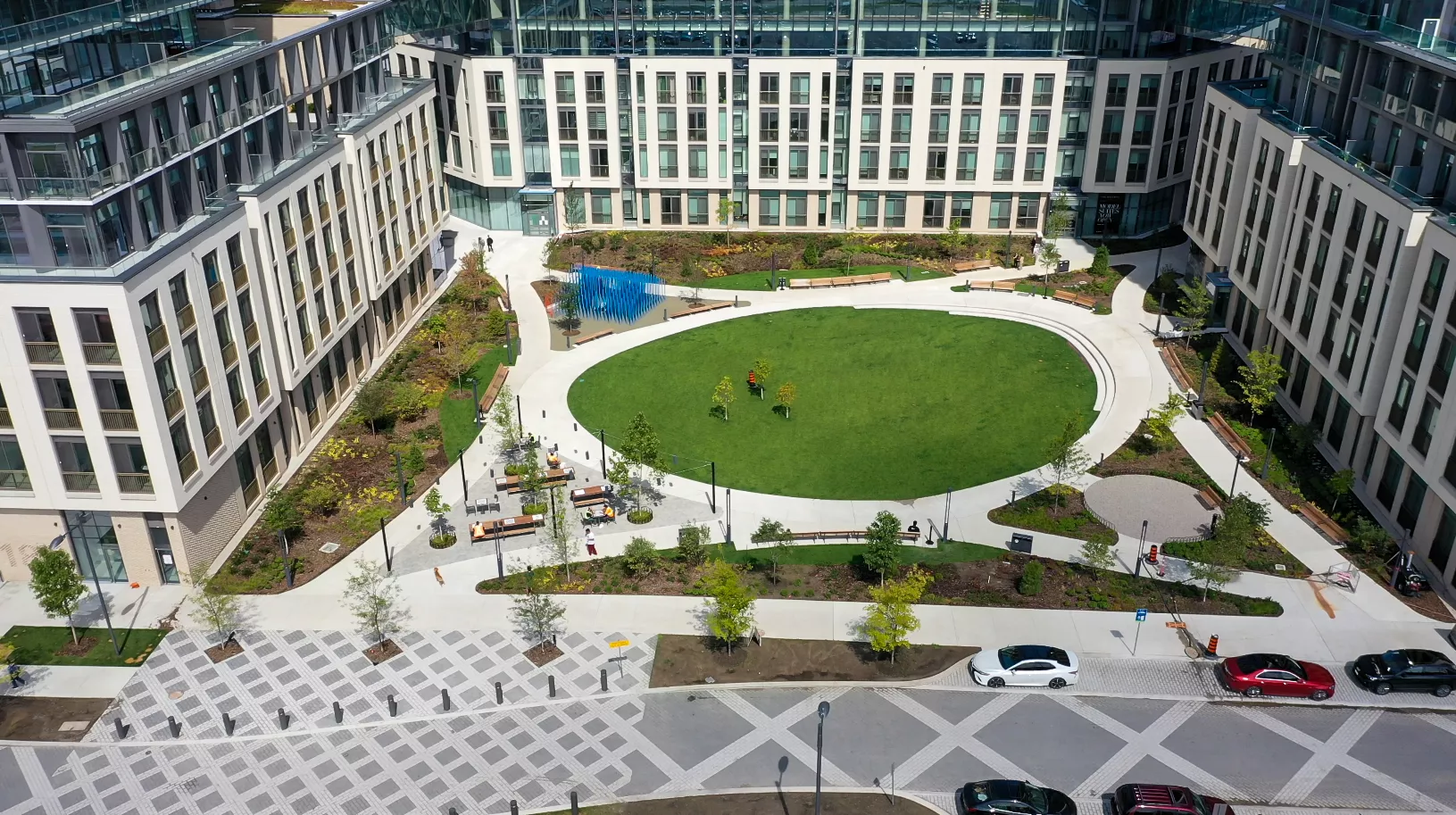 People enjoying a POPS including walking paths, a playground and a splashpad with condo towers in the background