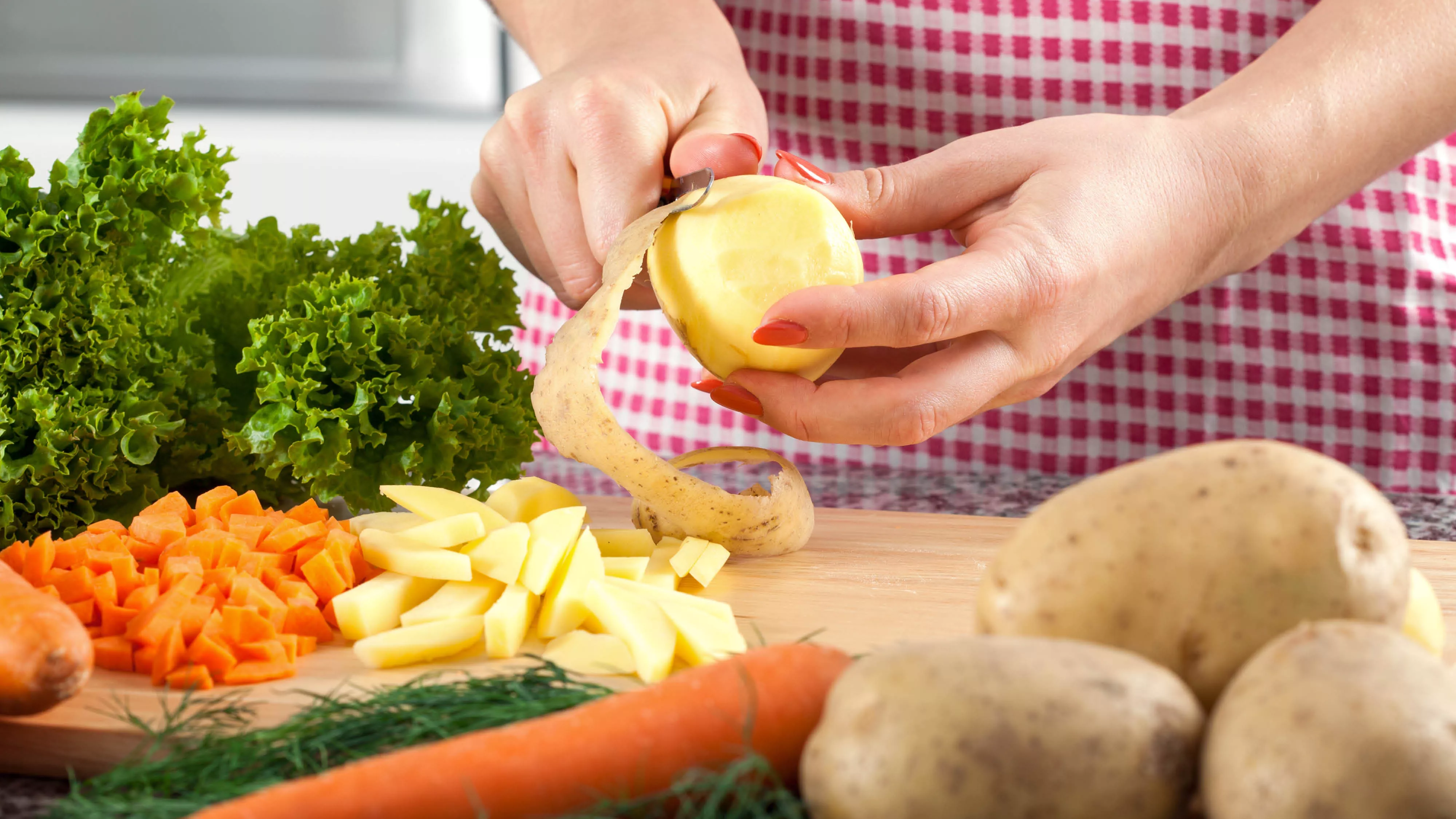 someone peeling a potato on a cutting board