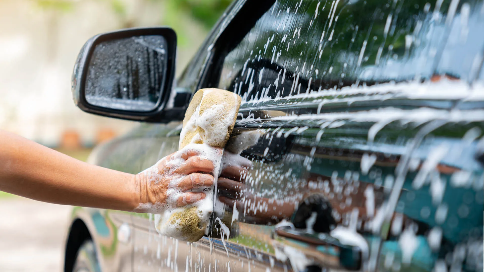 someone washing a black car with a sponge