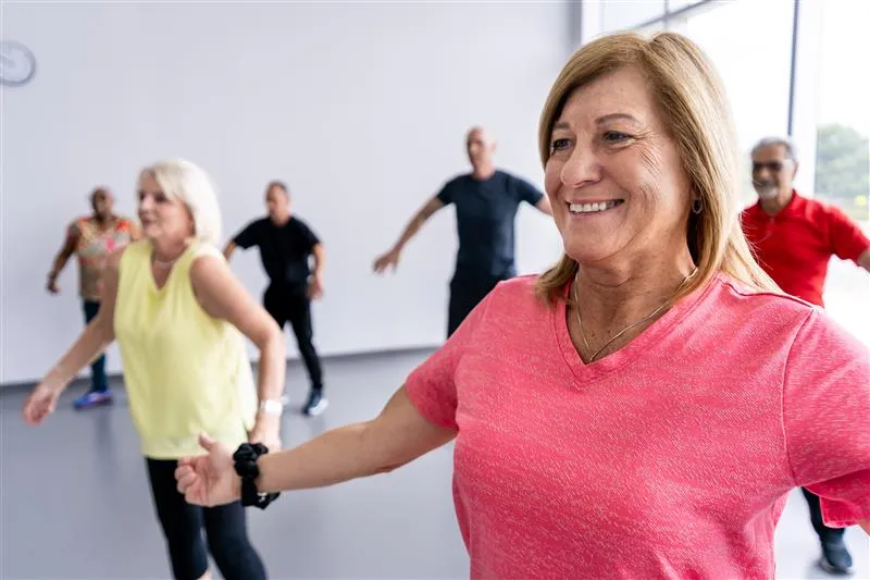 An older adult woman wearing a pink shirt participating in a rec class
