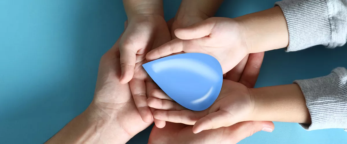 A group of hands holding a paper cut-out of a water droplet.